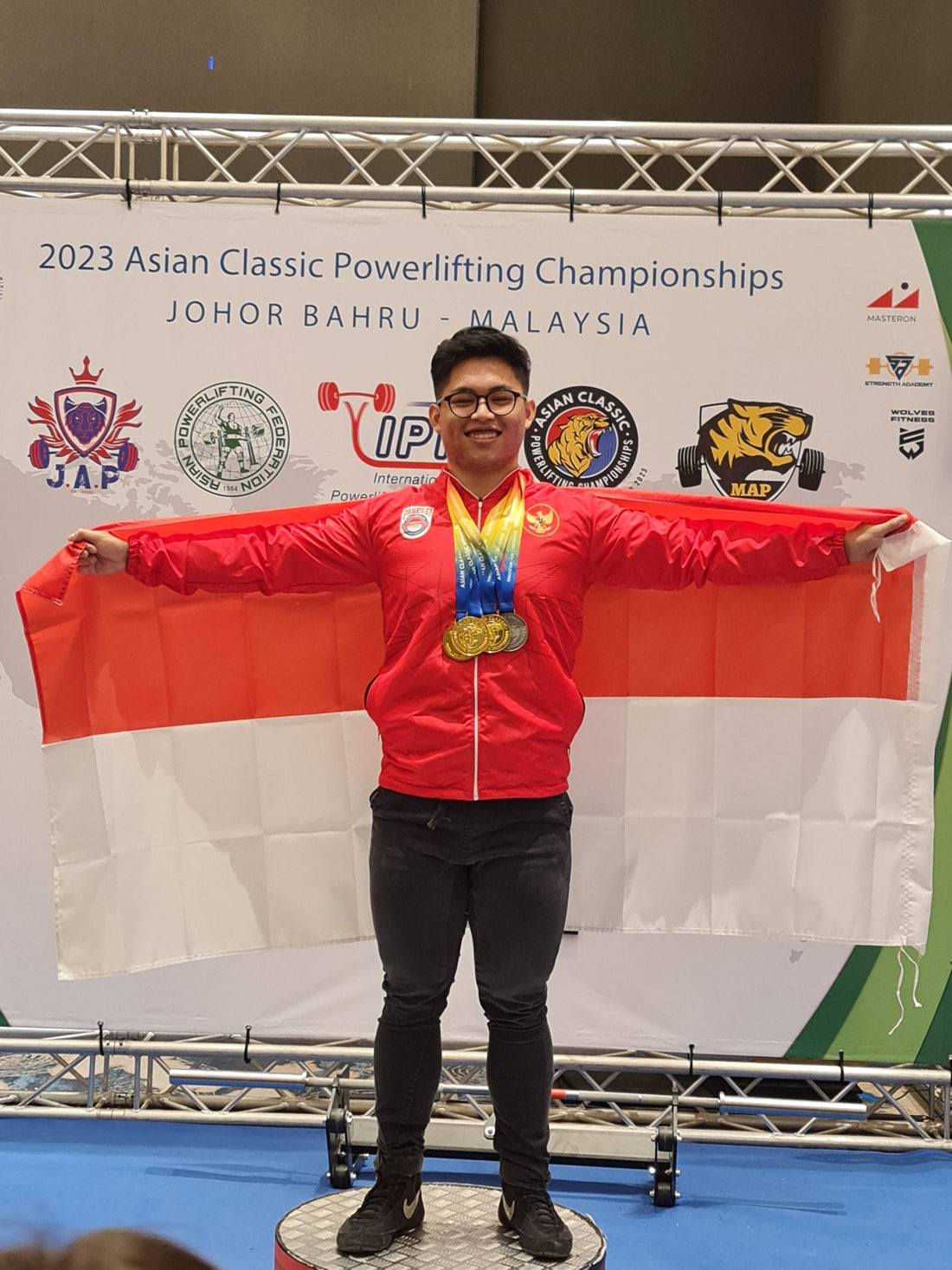 Indonesian Powerlifter, Andre Yoga, holding a flag at the IPF competition stage